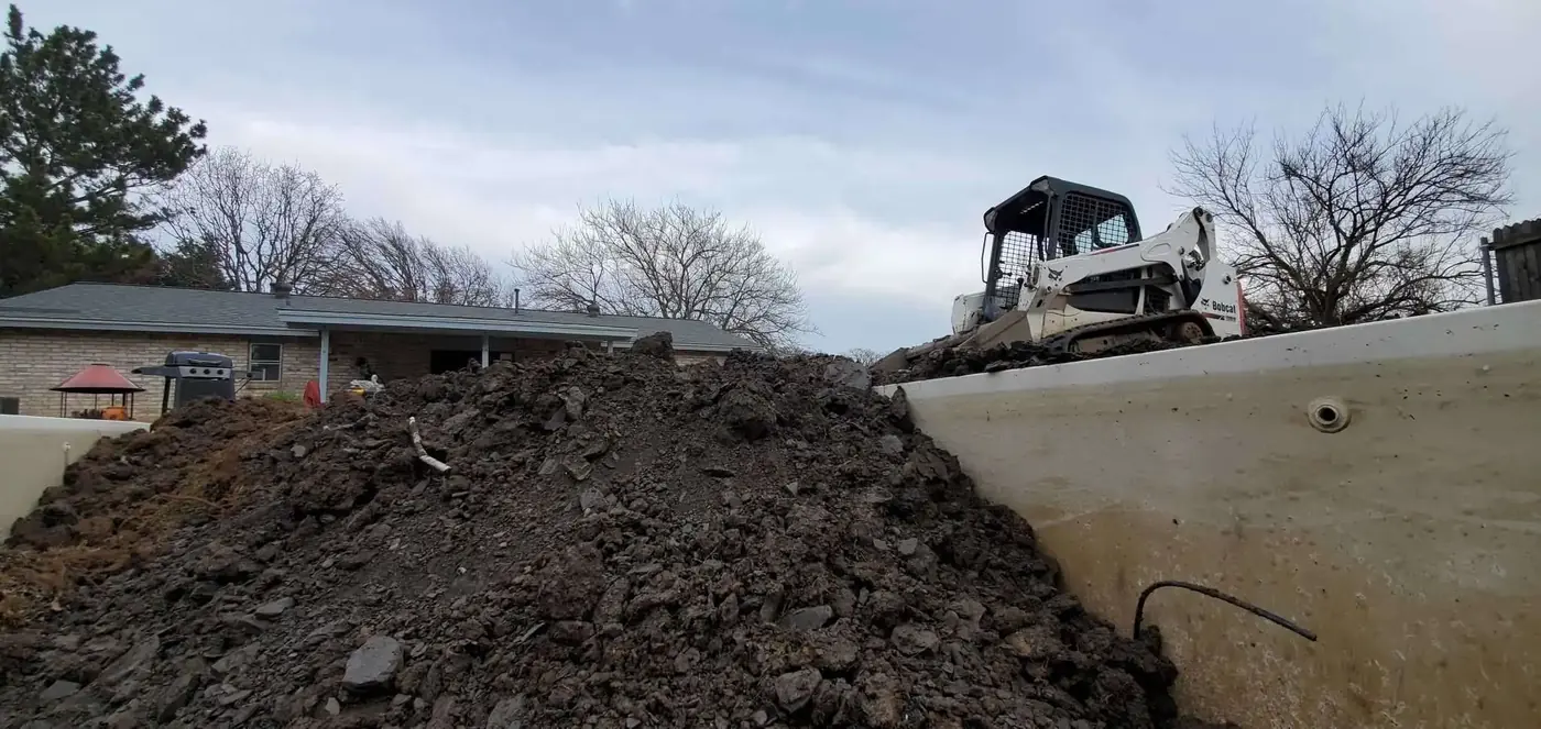 A loader moving fill dirt across a lot being raised to grade