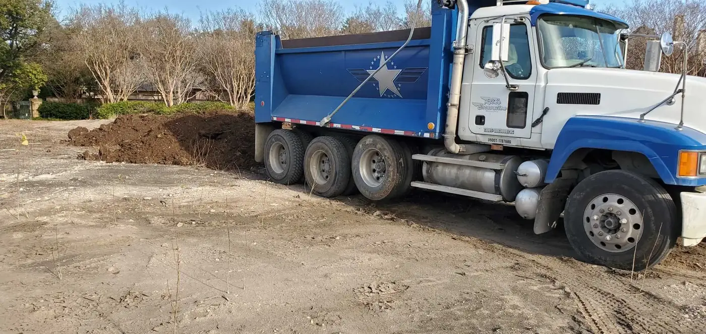 A dump truck tipping a load of clay fill dirt on site